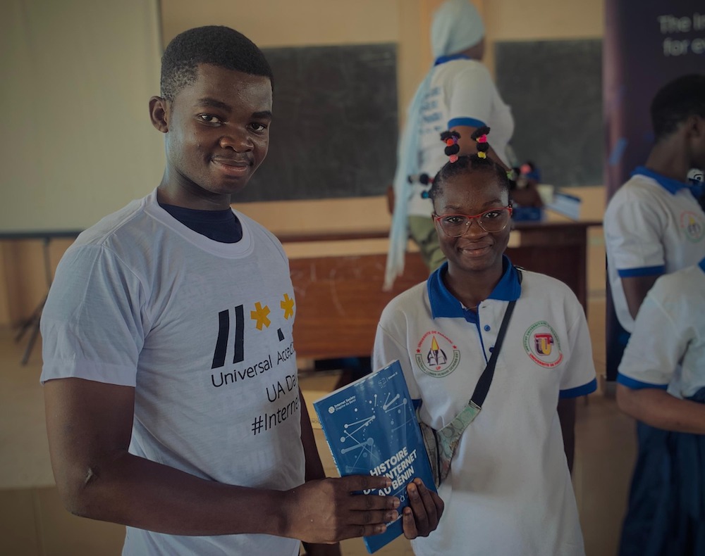 A man holding a book stands and smiles with a woman