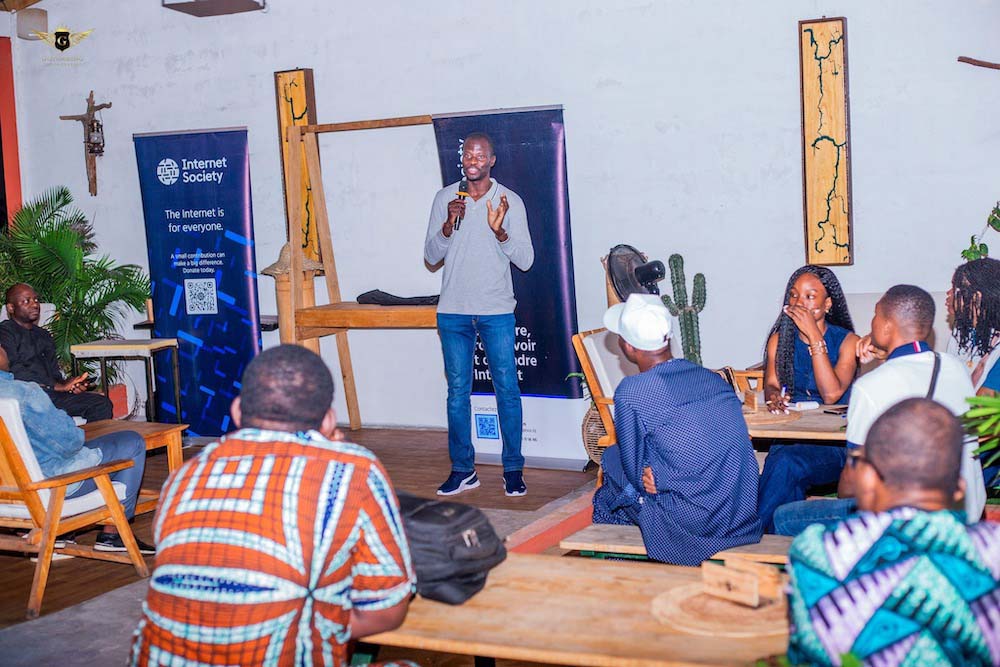 A man stands and speaks into a microphone at the Benin Chapter CafeNOG event