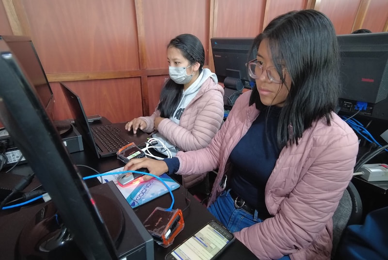 two girls with masks in front of the computers