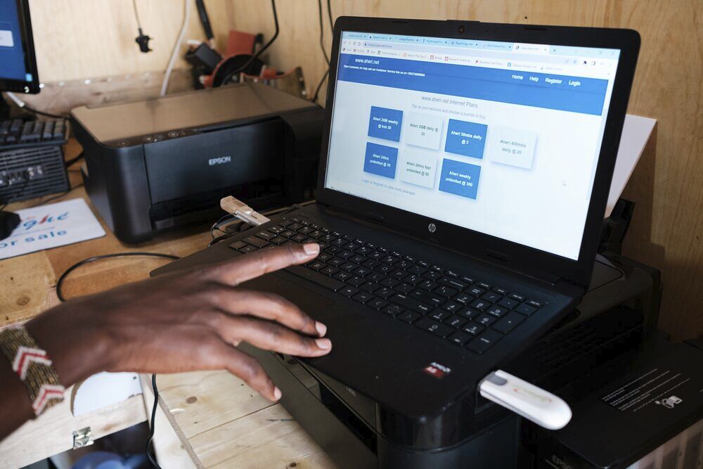 A hand in front of a laptop computer