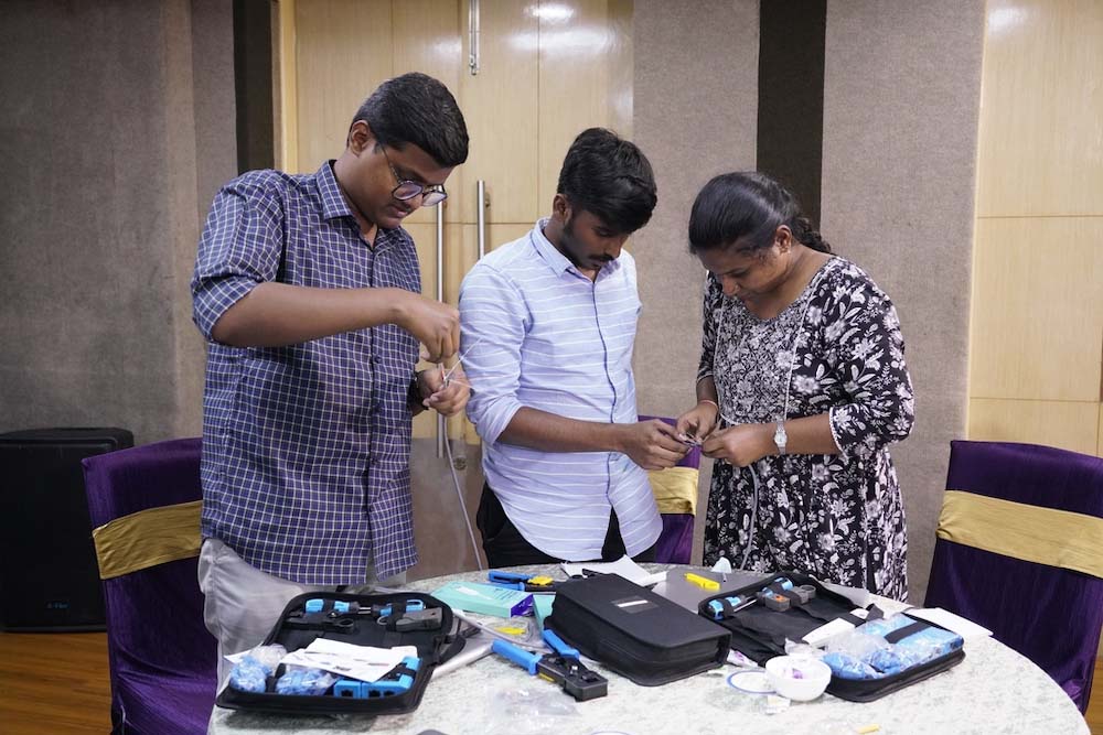 Three people look at wires and other networking supplies